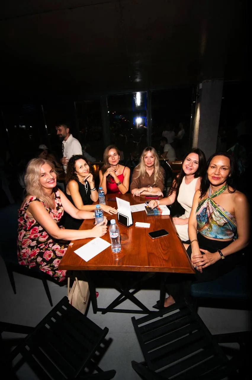 A group of female friends sitting at a wooden table in LEVEL Beach Batumi