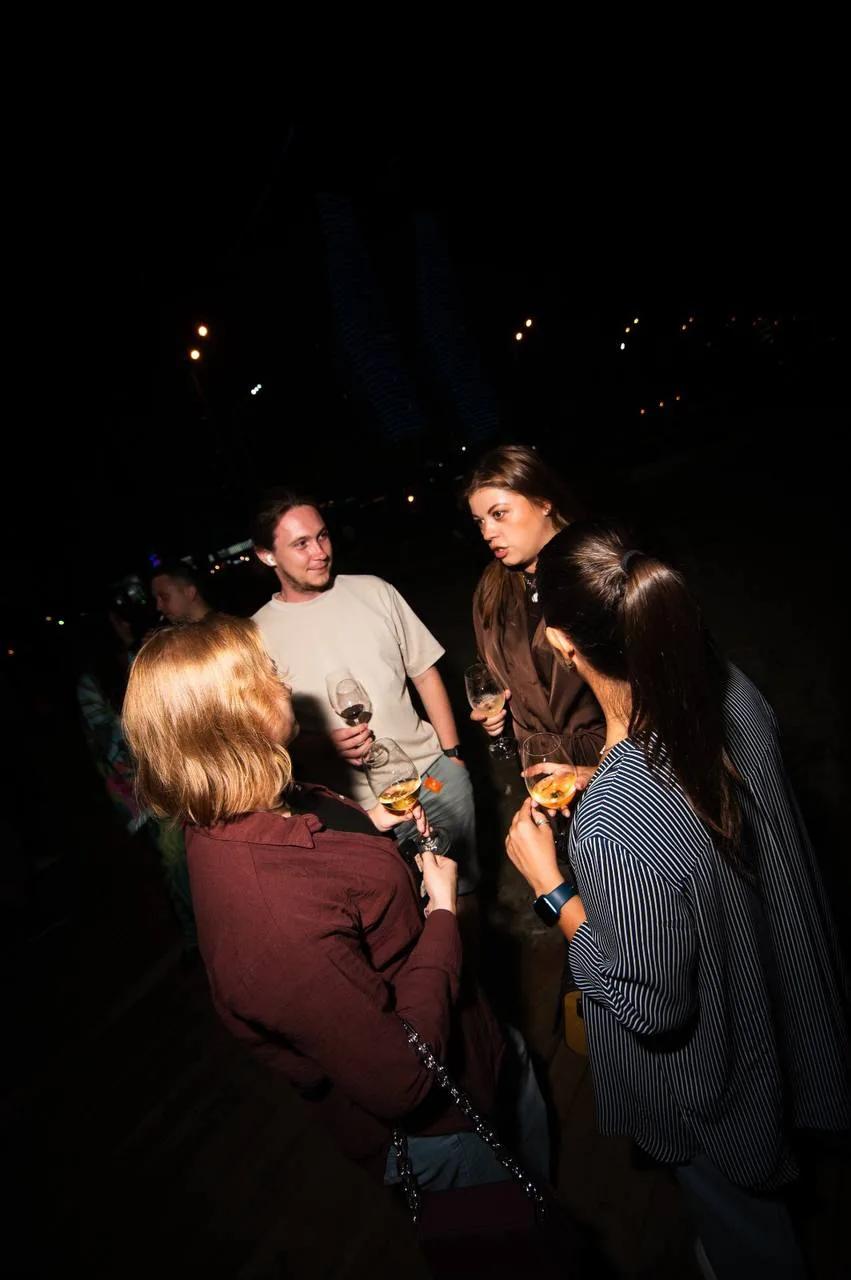 Friends chat with glasses in hand at LEVEL Beach Batumi beach bar at night